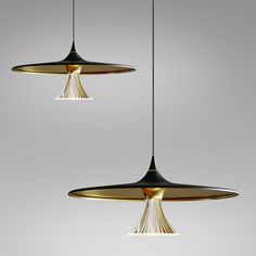 two pendant lights hanging from the ceiling, one is gold and the other is black