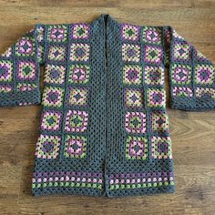 a crocheted jacket sitting on top of a wooden floor