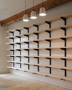 an empty room with some shelves and lights hanging from the ceiling in front of it