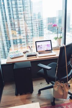 an office desk with a laptop on it and a chair in front of the window