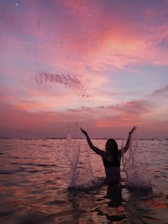 a woman standing in the water with her arms outstretched