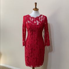 a red lace dress on a mannequin stand in front of a white wall