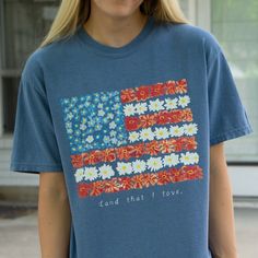 This t-shirt is based off my "Land That I Love" watercolor painting. It is an adaptation of the American Flag in red, white, and blue flowers which all have special meaning.    Red Zinnias - friendship, endurance, daily remembrance White Daisies - purity Blue Forget Me Not's - love for those we've lost   .: 100% ring-spun cotton .: Medium fabric (6.1 oz/yd² (206.8 g/m .: Relaxed fit .: Sewn-in twill label Garment-dyed goods should ALWAYS BE WASHED SEPARATELY BEFORE WEARING to avoid bleeding issu Blue T-shirt With American Flag Print For Spring, Multicolor Flag Print Casual T-shirt, Multicolor Flag Print Top For Memorial Day, Multicolor Crew Neck T-shirt With American Flag Print, Multicolor Flag Print Tops For Memorial Day, Memorial Day Multicolor Flag Print Top, Patriotic Multicolor Graphic Print T-shirt, Patriotic Multicolor T-shirt With Graphic Print, American Flag Print T-shirt For Spring