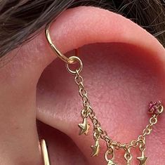 a close up of a person's ear with gold chain and stars on it