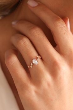 a woman's hand with a diamond ring on her left hand, wearing a gold band