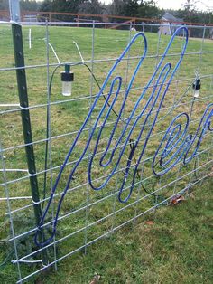 several blue hoses are attached to a wire fence in the middle of a grassy field