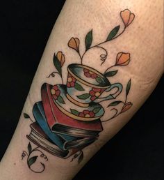 a tattoo with a stack of books and flowers on it