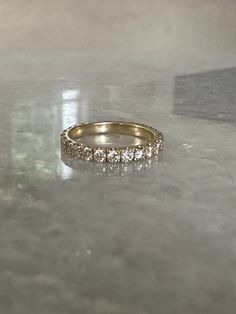 a gold wedding band with five round diamonds on the top and bottom, sitting on a marble surface