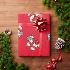 a present wrapped in red paper and tied with ribbon on top of a wooden table