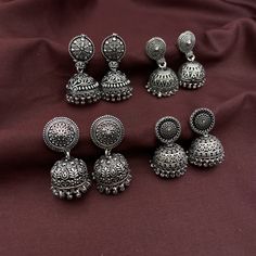 Introducing the exquisite 4-piece Jhumka Combo by Quirky Fashions, a must-have addition to your jewelry collection. Crafted from high-quality brass and adorned with a stunning German silver finish, these jhumkas combine traditional charm with modern elegance. Each pair features a convenient push-back closure, ensuring a secure and comfortable fit for all-day wear. Perfect for daily office wear, these jhumkas are designed to add a touch of sophistication to your professional attire. Whether you'r Bollywood Style Intricate Design Jhumkas, Heavy Drop Earrings Jhumkas, Diwali Drop Earrings Danglers, Heavy Drop Jhumkas, Navratri Drop Earrings Jhumkas, Gift Danglers For Navratri, Gift Oxidized Finish Jhumkas, Oxidized Finish Jhumkas For Gift, Festival Oxidized Danglers