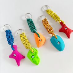 five different colored fish shaped key chains on white surface with metal clasps attached to each other