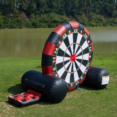 an inflatable dart set up on the grass next to a lake