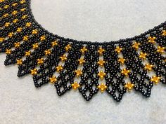 This hand beaded collar necklace features a main color of black with stunning gold accents. It adds a lovely dash of class to any outfit! Elegant Black Beads With Gold Details, Festive Handmade Black Necklace, Gold Choker With Black Beads For Parties, Black Beaded Necklace With Gold Beads For Party, Festive Gold Beaded Necklaces With Black Beads, Elegant Gold Choker With Colorful Beads, Festive Beaded Black Necklaces, Elegant Black Choker With Colorful Beads, Black Bib Necklace With Colorful Beads For Gift