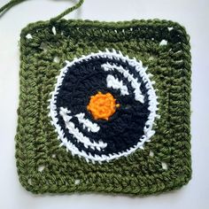 a crocheted square with a black and white circle in the center on top of it