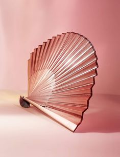 a pink fan sitting on top of a white table next to a red wall in the background