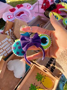 a hand holding a small toy with a purple bow on it