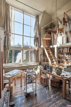 an old room with lots of books on the shelves and wooden tables in front of large windows