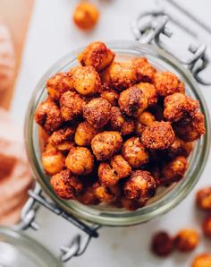 a glass bowl filled with fried food on top of a white table next to utensils