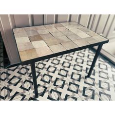 a tiled table sitting on top of a black and white floor next to a doorway