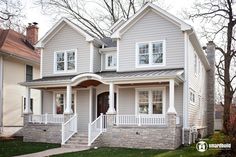 a two story house with white trim on the front porch and stairs leading up to it