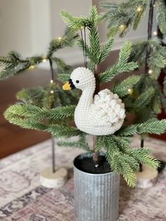 a crocheted duck sitting on top of a planter next to a christmas tree