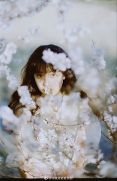 a woman standing in front of some white flowers