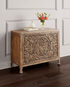 an ornate wooden cabinet with flowers on top