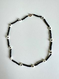 Elevate your style with this stunning black and white flower beaded choker necklace. Handcrafted with care, this unique piece blends elegance with a touch of edginess, making it perfect for any occasion. The monochrome color scheme ensures versatility, complementing both casual outfits and evening ensembles effortlessly. Whether you're treating yourself or searching for a thoughtful gift, this choker promises to add a dash of floral charm to your jewelry collection. Embrace timeless beauty with our black and white flower choker today! Details: ☆ Handmade item! ☆ Length: 15 in ☆ Perfect for: Everyday wear, special occasions, gifts Please make sure your address is correct before purchasing! For any questions don't hesitate to contact me :) Adjustable Black Flower Pendant Necklace, Black Adjustable Flower Pendant Necklace, Black Flower Choker As A Gift, Black Flower Choker For Gifts, Handmade Black Flower Necklace, Trendy Black Flower-shaped Jewelry, Black Flower Pendant Necklace With Charm, Adjustable Black Jewelry With Flower Charm, Black Flower Charm Jewelry