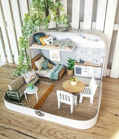 a dollhouse is shown with furniture and decor on the floor in front of a wooden fence