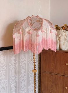 a pink and white lamp on top of a dresser