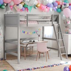 a loft bed with a desk underneath it and balloons all around the room on the wall