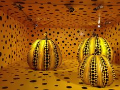 two black and white balls in a yellow room with polka dots on the wall behind them