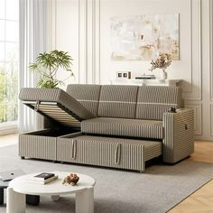 a living room with a couch, coffee table and plant on the floor in front of it