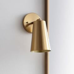 a wall mounted lamp on the side of a white wall next to a wooden pole