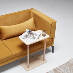 a small table with a magazine on it in front of a yellow couch and rug