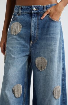 a woman wearing blue jeans with holes on the side and buttons in the back pocket