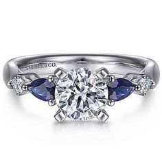 a diamond and blue sapphire engagement ring with three stones on the side, set in white gold