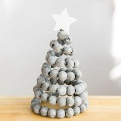 a christmas tree made out of marble beads on a wooden table with a white star above it