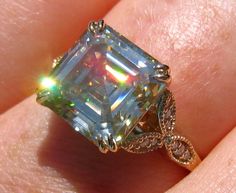 a woman's hand holding an engagement ring with a large diamond in the center