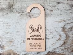 a wooden door hanger with a video game controller on it's side that says gaming in progress