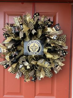 a new orleans saints wreath hanging on a red door with black and gold deco mesh