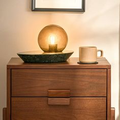 a table with a candle and a bowl on it next to a framed photo above