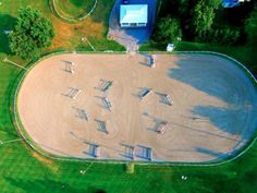 an aerial view of a skate park in the middle of a green field with trees