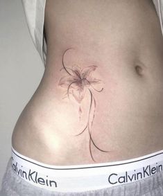 a woman's stomach with a flower tattoo on her lower belly and the words calvinklen written below it