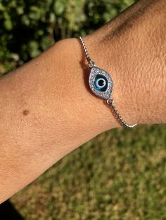 "925 Sterling Silver Double Sided Evil Eye Bracelet: Almond shaped blue Evil Eye Which is enhanced with CZ's on one side of the mounting while the other is without stone. Two exceptionally beautiful ways for the bracelet. The bracelet is 6.5\" in and has a extender chain of 1 1/2\"in to extend total to 8\" in with a Lobster Claw Lock Measurements Approximately: Weight: 5.00 g / 0.18 oz Length: 17.00 cm / 6.5 in Width: 15.00 mm / 0.59 in Height: 10.00 mm / 0.39 in" Silver Bracelet With Cubic Zirconia Stones, Elegant Silver Evil Eye Jewelry, Elegant Sterling Silver Evil Eye Bracelets, Silver Evil Eye Bracelets In Sterling Silver, Sterling Silver Evil Eye Bracelets, Sterling Silver Evil Eye Bracelet In Silver, Silver Cubic Zirconia Evil Eye Bracelet Gift, Silver Evil Eye Bracelet With Cubic Zirconia, Silver Sterling Silver Bracelet With Stones