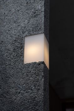 a light that is on in the side of a stone wall next to a door