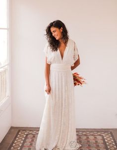 a woman in a white dress standing by a window