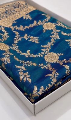 an open box with a blue and gold cloth in the bottom corner on a white surface