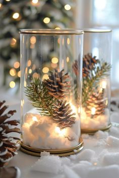 two glass jars filled with snow and pine cones