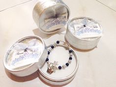 three silver containers with bracelets and necklaces in them sitting on a white table